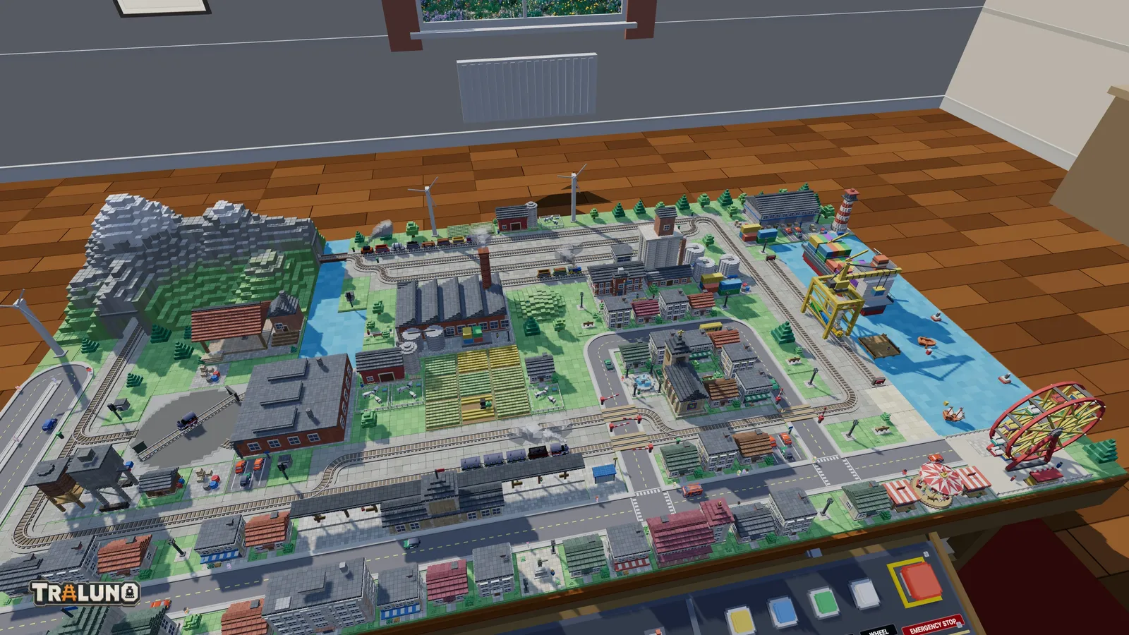 The Traluno demo layout from the front of the table in afternoon light: the mountain in the back-left corner, the factory and fields in the middle, the town and station along the front, the harbour with its crane, cargo ship and lighthouse on the right, and the fair with its ferris wheel in the front-right corner.