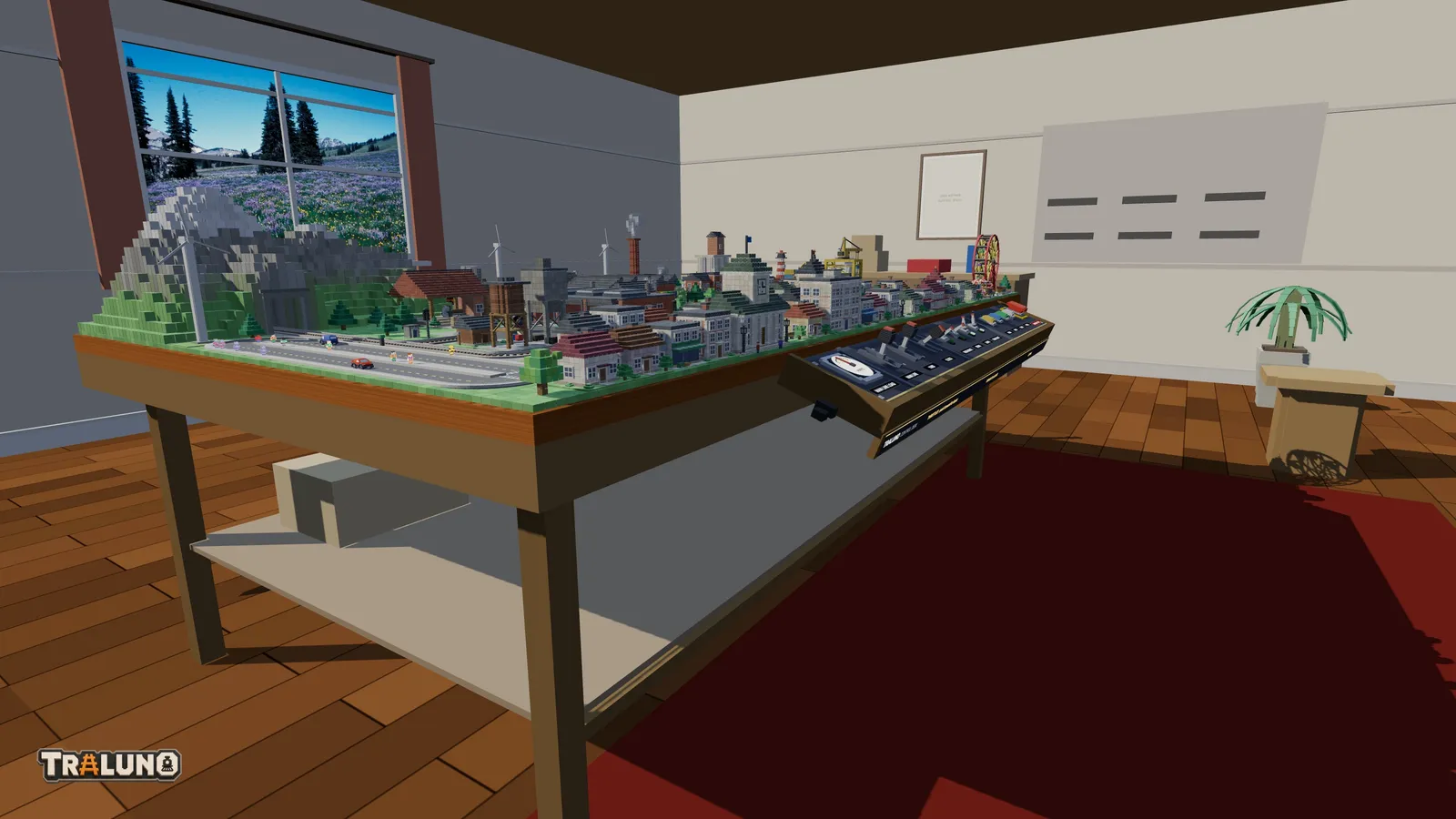 A Traluno layout seen from beside its table in the hobby room: the table's wooden edge and legs, the control desk fixed along the front, a mountain and a town on top, and a window in the wall behind.