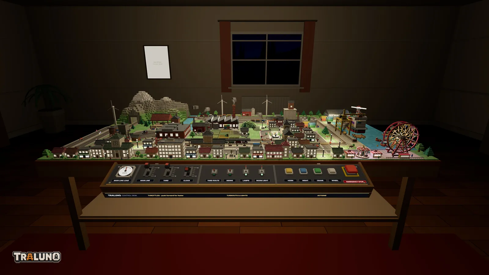 The hobby room at night: the window dark, the walls dim, and the table and its control desk lit from above, with lit windows across the town.